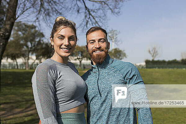 Lächelndes junges Paar in einem öffentlichen Park an einem sonnigen Tag