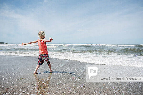 USA  Kalifornien  Ventura  Rückansicht eines Jungen am Strand mit ausgestreckten Armen