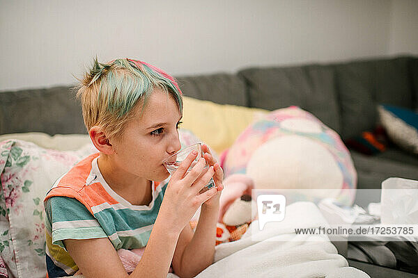 Canada  Ontario  Boy with colorful hair drinking water on sofa
