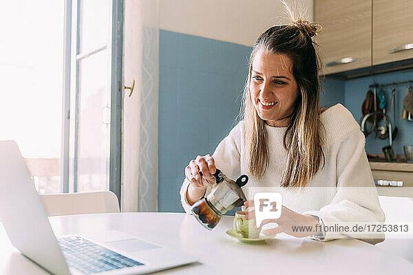 Italien  Junge Frau trinkt Kaffee und schaut auf den Laptop
