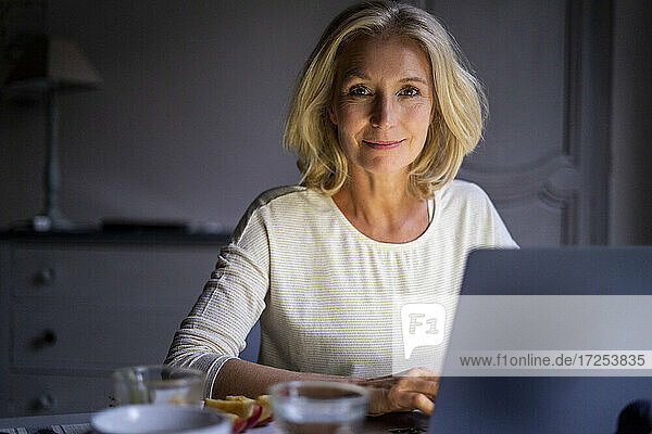 Portrait of smiling mature woman using laptop at home
