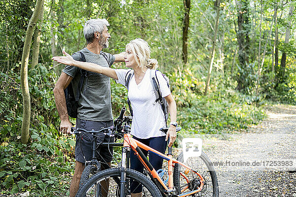 Mature couple showing directions to each other in forest