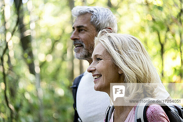 Lächelndes reifes Paar schaut im Wald weg