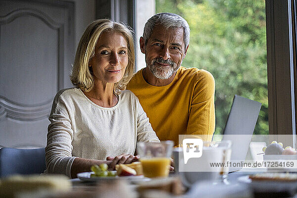 Portrait of smiling mature couple using laptop at home