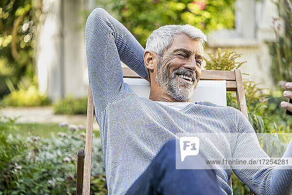 Lächelnder reifer Mann mit Videoanruf auf Smartphone im Hinterhof