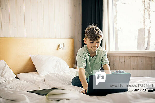 Boy using laptop while studying at home