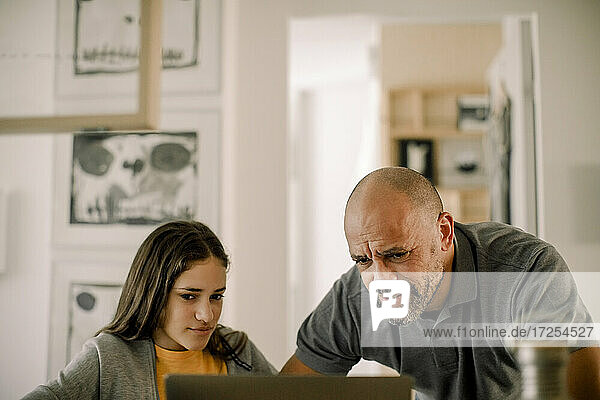 Father and daughter using laptop in kitchen at home