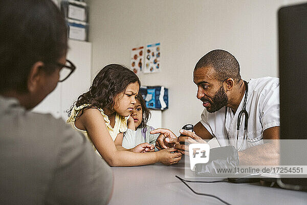 Male doctor showing glaucometer to girl in medical clinic