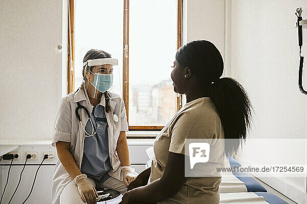 Female medical expert consulting young patient at medical clinic during COVID-19