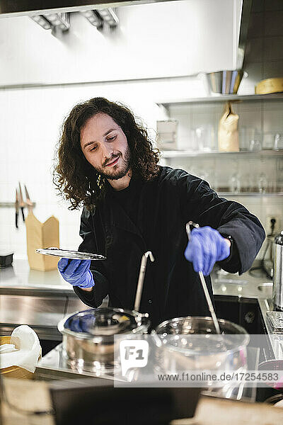 Männlicher Koch rührt bei der Zubereitung von Speisen in der Küche eines Restaurants