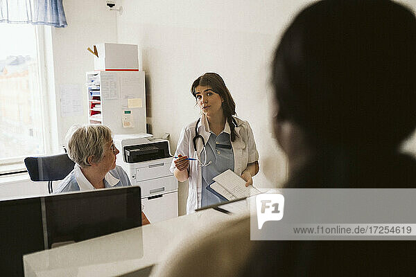 Weiblicher Arzt diskutiert mit älteren Krankenschwester beim Betrachten der Patienten in der medizinischen Klinik
