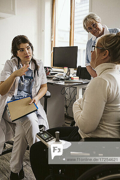 Mitarbeiterin im Gesundheitswesen im Gespräch mit einer behinderten Frau in einer Arztpraxis