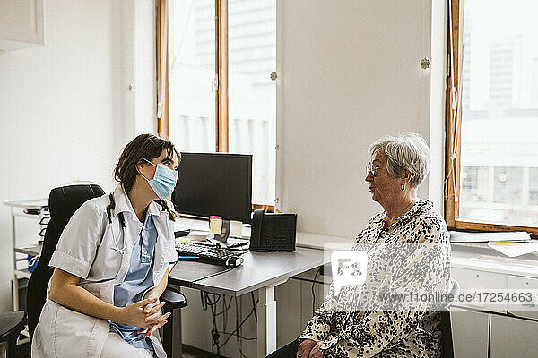Female doctor consulting senior patient during COVID-19