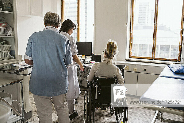 Rückansicht eines behinderten Patienten mit Ärztin und Krankenschwester in einer medizinischen Klinik