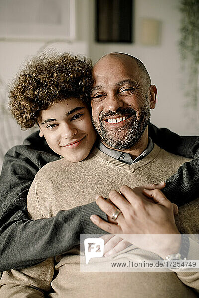 Porträt eines lächelnden Jungen  der seinen Vater umarmt