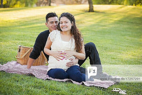 Friedliches schwangeres hispanisches Paar im Park im Freien