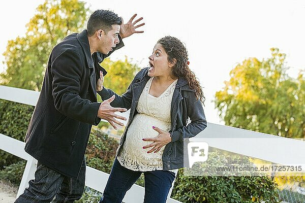 Panische schwangere Frau und Mann mit Hand auf Bauch außerhalb
