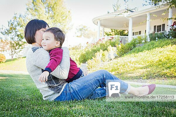 Glückliche chinesische Mutter hat Spaß mit ihrem gemischtrassigen kleinen Sohn im Freien