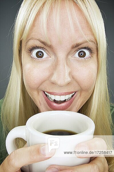 Beautiful woman enjoys her coffee against a grey background