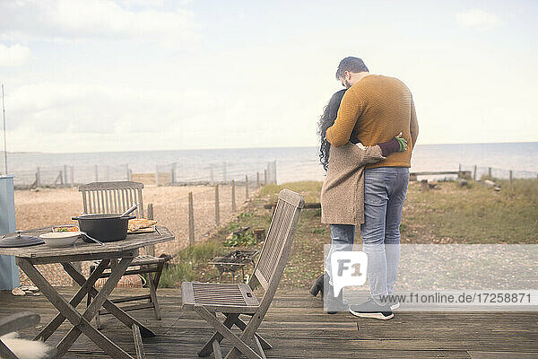 Affectionate couple hugging on ocean beach patio
