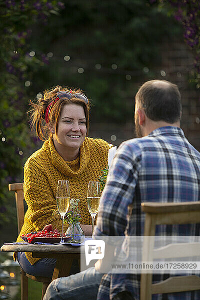Glückliches Paar genießt Champagner und rote Johannisbeeren am Gartentisch