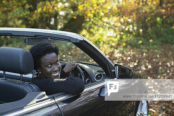 Portrait happy woman driving convertible in autumn park