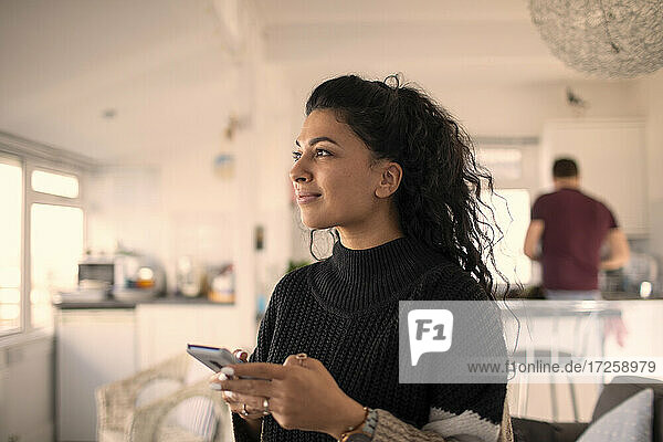 Smiling beautiful woman using smart phone at home