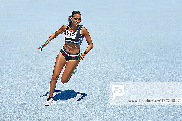 Female track and field athlete on sunny blue track
