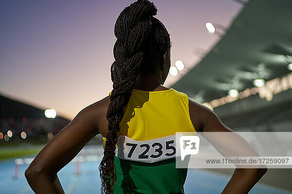 Female track and field athlete with long black braids in stadium