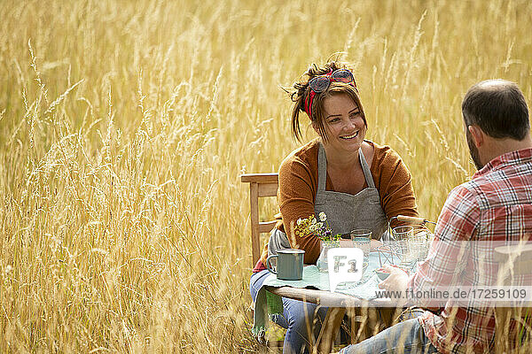 Glückliches Paar im Gespräch am Tisch im sonnigen Sommer hohes Gras