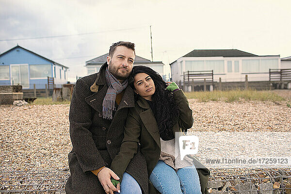 Serene couple in winter coats outside beach houses