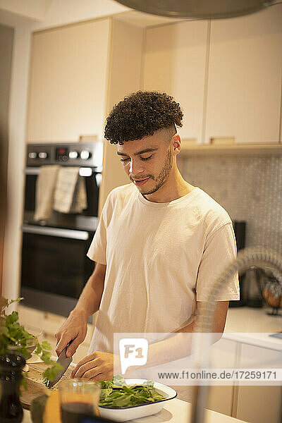 Junger Mann Kochen Schneiden von Gemüse auf Küchentheke