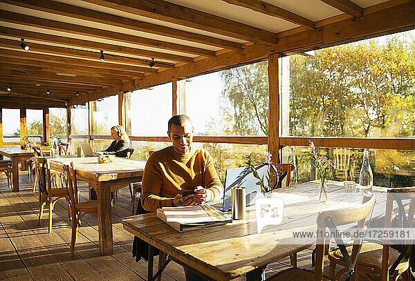 Geschäftsmann mit Smartphone in sonnigen Herbst-Café