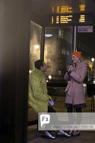 Stilvolle junge Paar im Gespräch an der Stadt Bushaltestelle in der Nacht