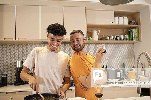 Glückliche Homosexuell männliches Paar Kochen und Trinken Wein in der Küche
