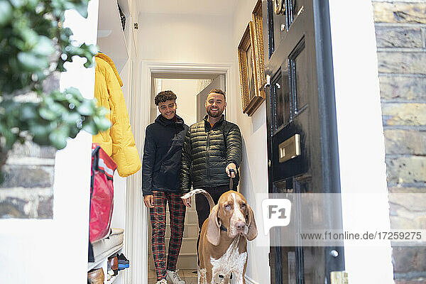 Happy gay male couple leaving house to walk dog