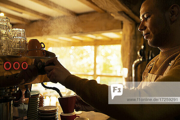 Männlicher Barista bereitet Cappuccino an der Espressomaschine im Café zu