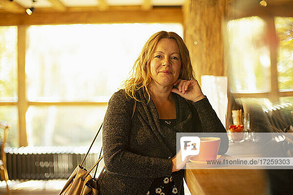 Porträt glückliche Frau bestellt Cappuccino im Café Theke