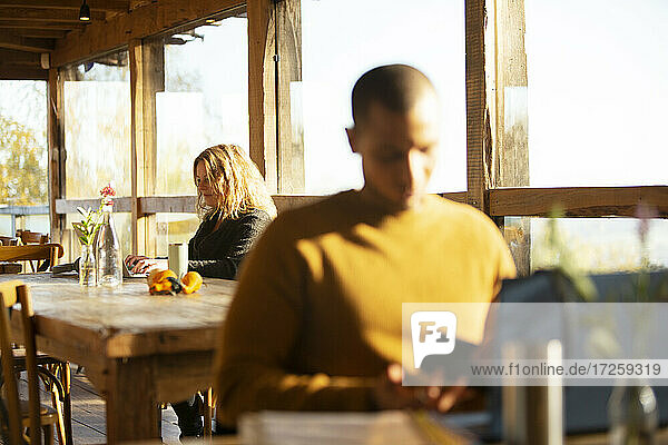 Geschäftsleute arbeiten an Laptops in sonnigen Cafe