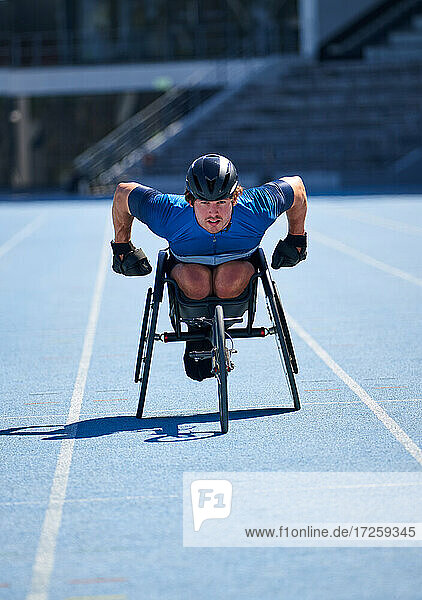 Fokussierter männlicher Rollstuhlsportler beim Training auf sonniger blauer Sportbahn