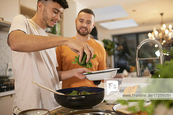 Homosexuell männliches Paar Kochen mit frischem Spinat in der Küche