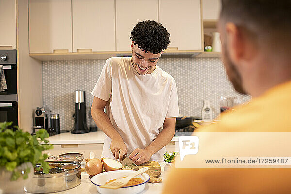 Young man cooking cutting onion in kitchen