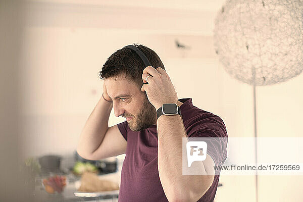 Man with smart watch and headphones listening to music at home