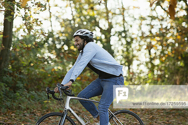 Glücklicher junger Mann fährt Fahrrad im Herbst Park