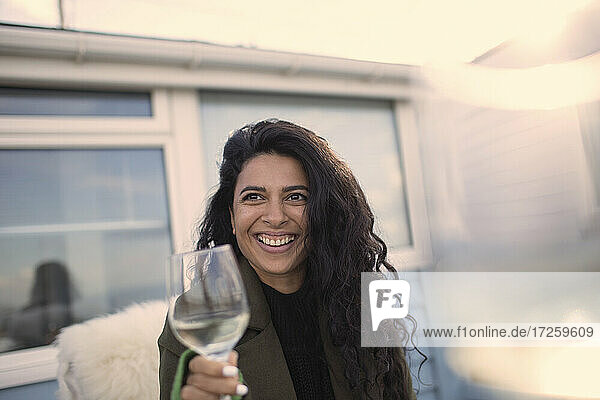 Glückliche sorglose Frau genießt Weißwein auf der Terrasse