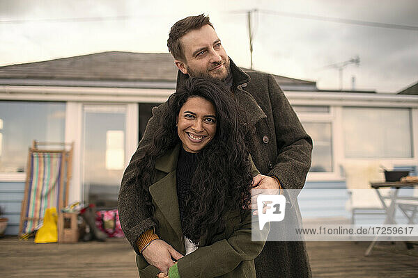 Porträt glückliches Paar in Wintermänteln auf Terrasse