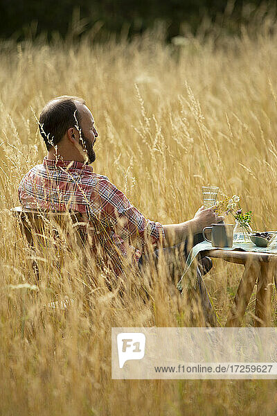 Mann entspannt am Tisch im sonnigen Sommer hohes Gras