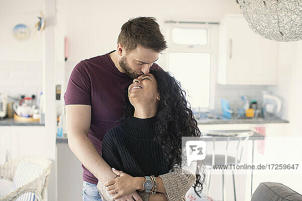Glücklich zärtliches Paar umarmt und küsst in der Küche