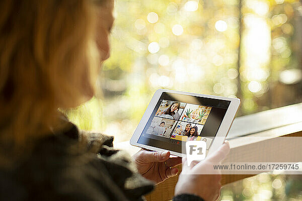 Woman video chatting with family on digital tablet screen