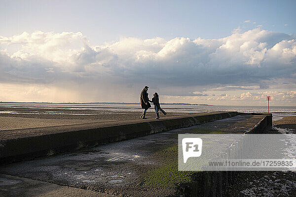 Glückliches Paar in Wintermäntel auf sonnigen Ozean Strand Steg